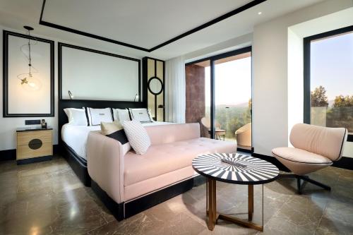 a bedroom with a bed and a couch and a chair at BLESS Hotel Ibiza - The Leading Hotels of The World in Es Cana