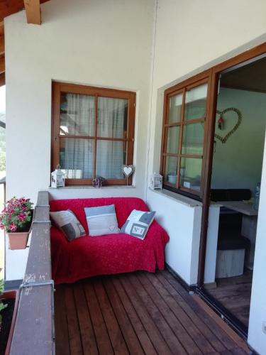 a red couch sitting on a wooden deck at Ferienwohnung Bergerlebnis Ötscher in Lackenhof