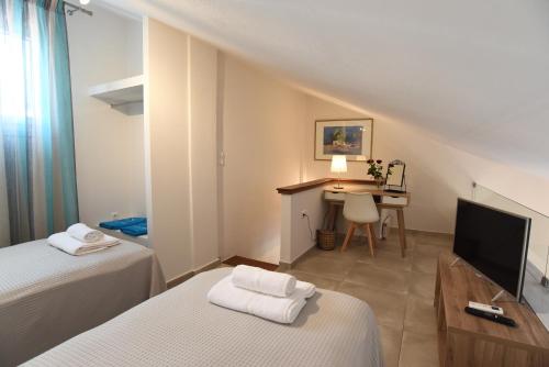 a room with two beds and a desk with a television at Melia Luxury Suite with pool in Iraklitsa