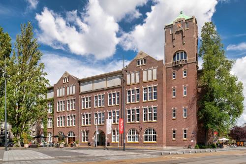 un gran edificio de ladrillo con una torre de reloj en Stayokay Hostel Amsterdam Oost, en Ámsterdam