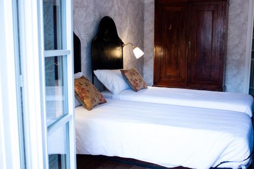 a bedroom with two beds with white sheets and a window at Locanda Capolago in Colico