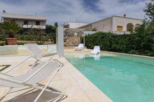 two chairs and a swimming pool in a house at Dimora San Quirico - bed e breakfast - Cisternino in Cisternino