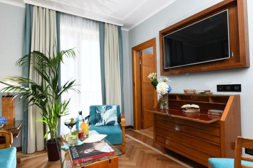 a living room with a television and a blue chair at Bettoja Hotel Mediterraneo in Rome