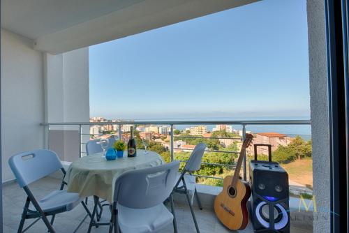 a balcony with a table and chairs and aoustic guitar at M Apartments in Bar
