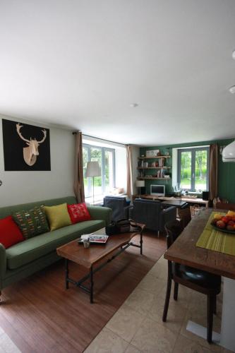 a living room with a green couch and a table at Le Repere du Cerf in Herbeumont