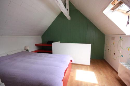 a bedroom with a white bed and a green wall at Le Repere du Cerf in Herbeumont