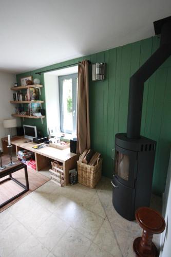 a living room with a stove and a desk and a window at Le Repere du Cerf in Herbeumont