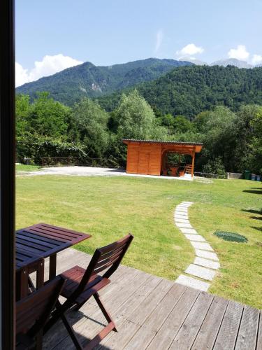 a wooden deck with a table and chairs and a field at Apartments Maligoj in Tolmin