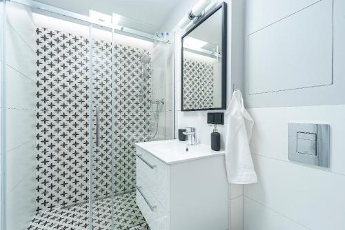a white bathroom with a shower and a sink at IV apart in Gdynia
