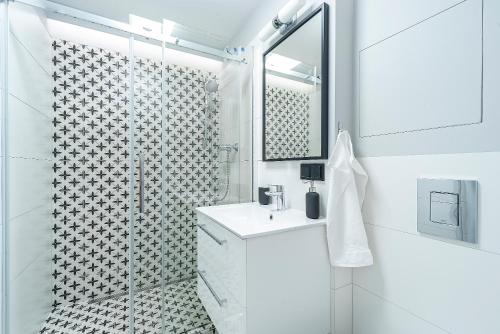 a white bathroom with a shower and a sink at 4 Apart in Gdynia