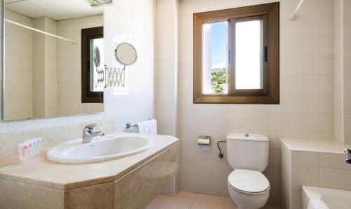 a bathroom with a sink and a toilet and a mirror at Hotel Gaya in Paguera