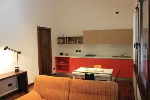 a living room with a table and a kitchen with red cabinets at 3 Tesori B&B in Castel dʼArio