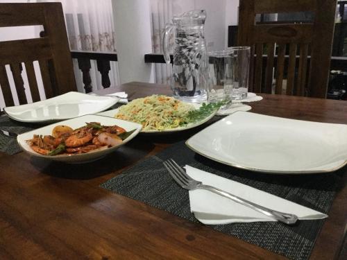 a wooden table with two plates of food on it at Kandyan Lounge in Kiribatkumbura