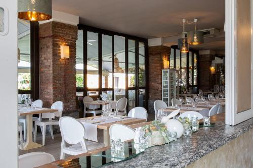 a restaurant with tables and white chairs and windows at La Bergamina Hotel & Restaurant in Arcore
