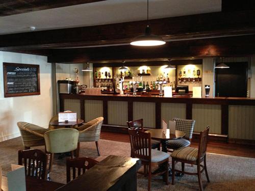 a restaurant with tables and chairs and a bar at Beverley Inn & Hotel in Edenthorpe