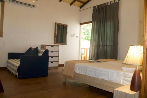 een slaapkamer met een bed, een stoel en een raam bij Gecko Lipe Resort in Ko Lipe