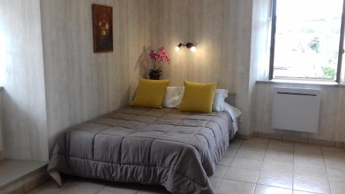 Un dormitorio con una cama con almohadas amarillas y una ventana en Le Petit St Jacques en Le Puy-en-Velay