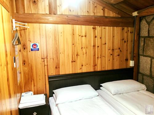 a bedroom with two beds in a wooden wall at Qin Bi Qingnian Homestay in Beigan