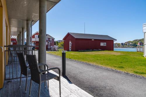 a porch with two chairs and a red barn at Sommarøy Arctic Hotel Tromsø in Sommarøy