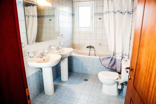 een badkamer met 2 wastafels, een bad en een toilet bij Peloponnese Luxury Residence in Psathopirgos