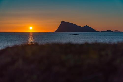 a sunset over the water with a mountain in the background at Sommarøy Arctic Hotel Tromsø in Sommarøy