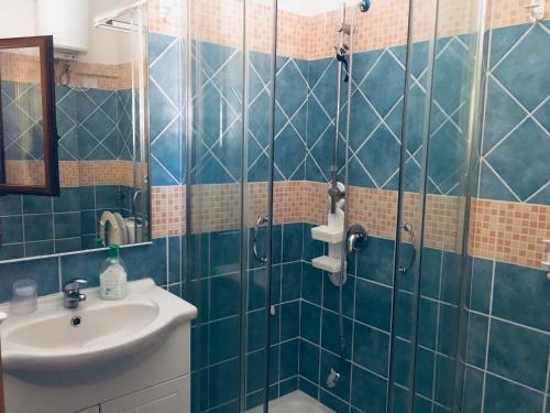 uma casa de banho em azulejos azuis com um lavatório e um chuveiro em Albergo Villamarina em Santa Teresa Gallura