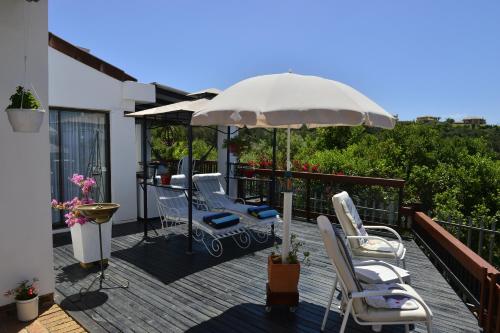 a patio with chairs and an umbrella on a deck at 22 Julia B&B in Plettenberg Bay