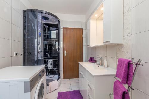 a bathroom with a sink and a washing machine at Apartments Marica in Skrbčići