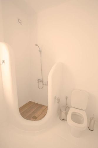 a white bathroom with a toilet and a mirror at Villa Phoebe in Mikonos