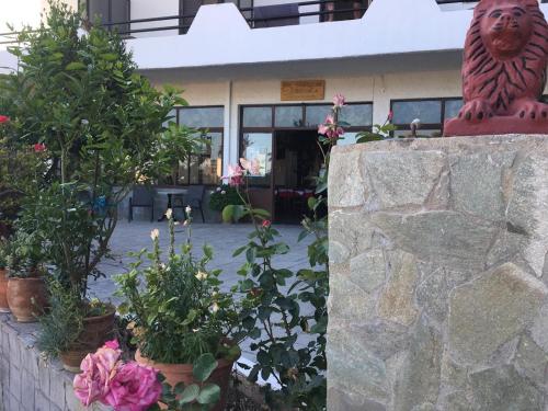 a stone wall with plants and flowers in front of a building at Archontika Apartments in Kerames