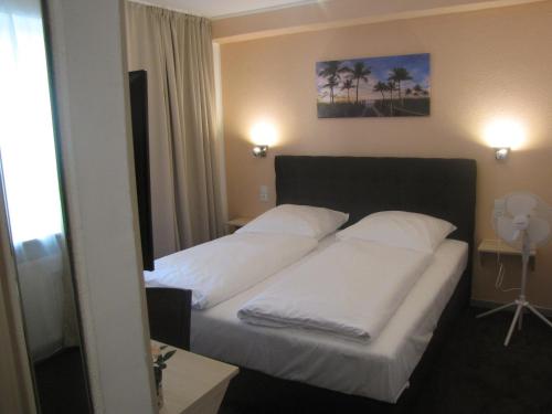 Ce lit se trouve dans une chambre d'hôtel dotée de 2 oreillers blancs. dans l'établissement Milano Hotel, à Hambourg