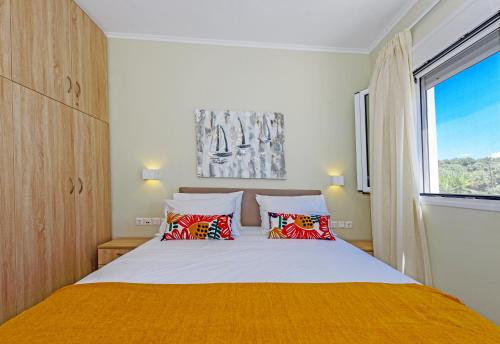 a bedroom with a bed with red pillows and a window at Villa Ellie - heated pool, playground, garden & BBQ! in Vederoi