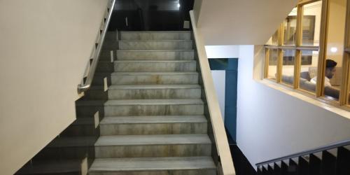 a staircase in a building with a man sitting on a bed at Hotel Mahendra in Jālgaon