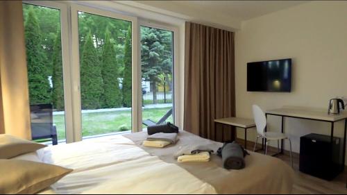 1 dormitorio con cama, escritorio y ventana en WODNIK usługi hotelarskie, apartamenty, en Rowy