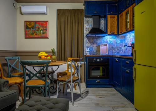 une cuisine avec des armoires bleues, une table et des chaises dans l'établissement Vitality Guest House, à Veliko Tarnovo