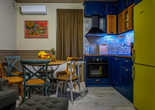 una cucina con armadi blu, tavolo e sedie di Vitality Guest House a Veliko Tŭrnovo
