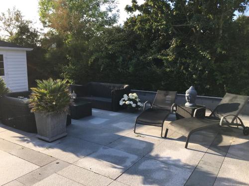 a patio with two chairs and a couch and a table at Beach bungalow Hellevoetsluis in Hellevoetsluis
