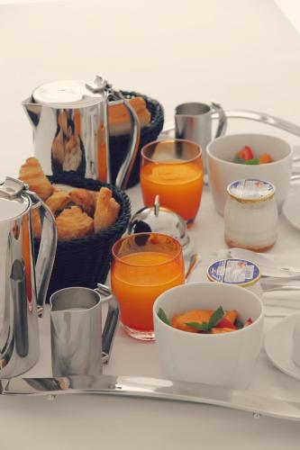 a table topped with bowls of food and orange juice at Le Grand Hotel de la Plage in Biscarrosse-Plage