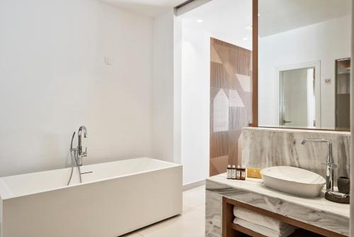 a white bathroom with a sink and a mirror at Myconian Korali Relais & Chateaux in Mýkonos City