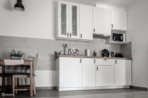 a white kitchen with white cabinets and a table at Aranymandula apartmanok in Balatonakali