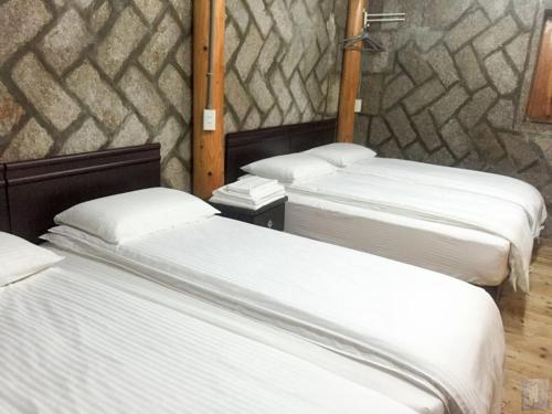a room with three beds and a stone wall at Qin Bi Qingnian Homestay in Beigan