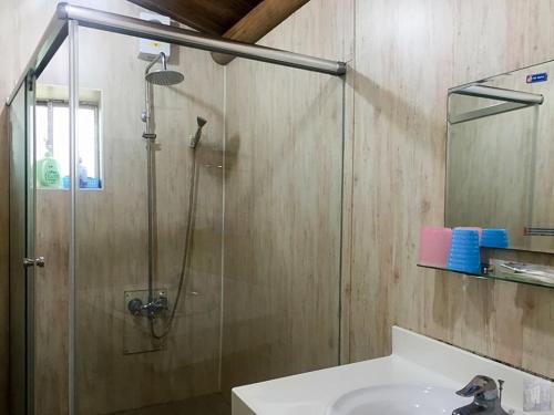 uma casa de banho com uma cabina de duche em vidro e um lavatório. em Qin Bi Qingnian Homestay em Beigan