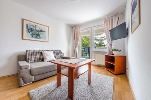 a living room with a table and a couch at Apartamenty Sun & Snow w Rezydencji Bielik in Międzyzdroje