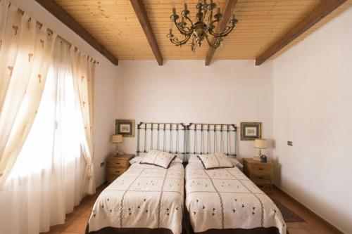 a bedroom with a bed and a chandelier and a window at Casa Rural Rio Agueda in Ciudad-Rodrigo