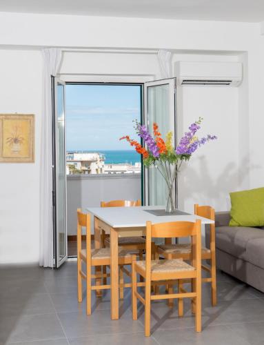 a dining room with a table with a vase of flowers at Svevo Sea House in Vieste