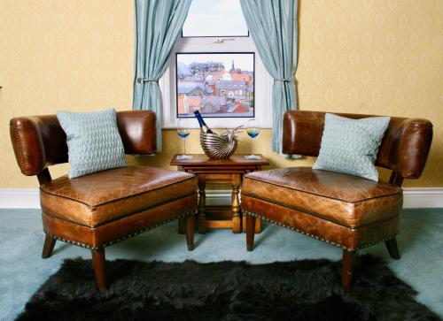 duas cadeiras de couro e um banco numa sala de estar em The Mainstay Luxury Boutique Rooms with Private Parking em Whitby
