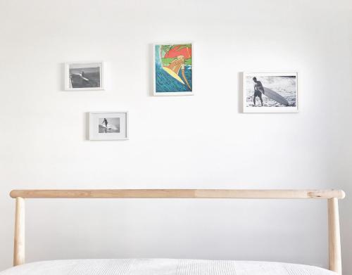 a bedroom with a white wall with pictures on the wall at Bay House Baleal - Surfboard included in Ferrel