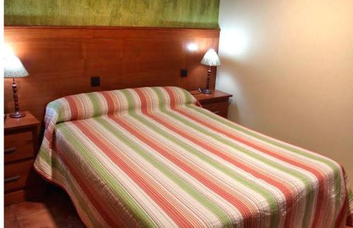 1 cama con colcha a rayas en un dormitorio en Nuevo Hostal Paulino, en Trujillo