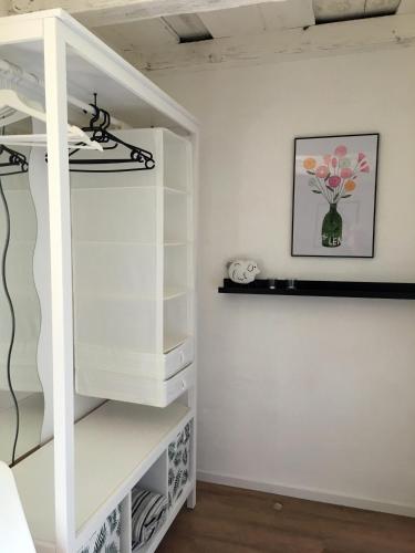 a white closet with a shelf and a vase of flowers at Gästewohnung A+C Bovet in Strasen