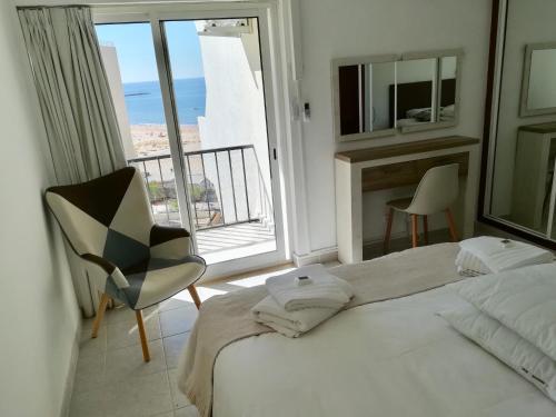 sypialnia z łóżkiem, krzesłem i oknem w obiekcie Acropole Algarve Beach Apartment w mieście Portimão
